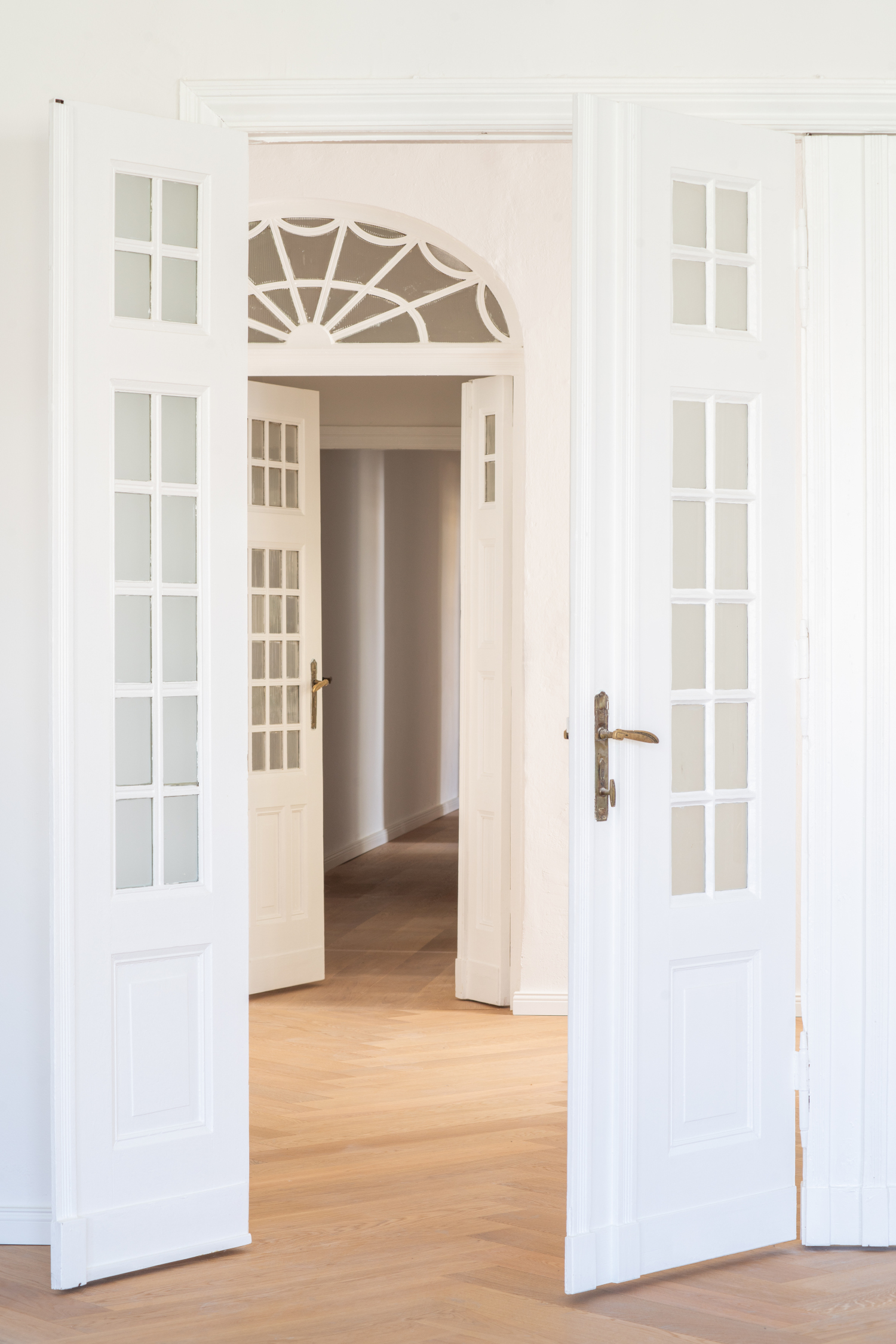 Historische Doppeltüren in einem sanierten Altbau, die sich zum Wohnzimmer öffnen und den originalen Charme des Gebäudes bewahren.