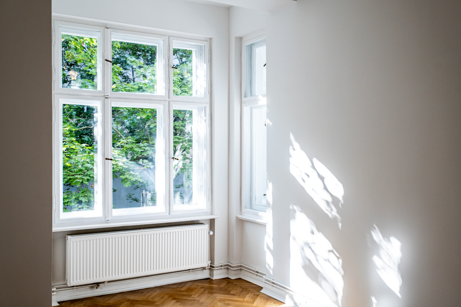 Large window front of a renovated old building with a view of the greenery, which makes the room appear light-flooded and inviting.