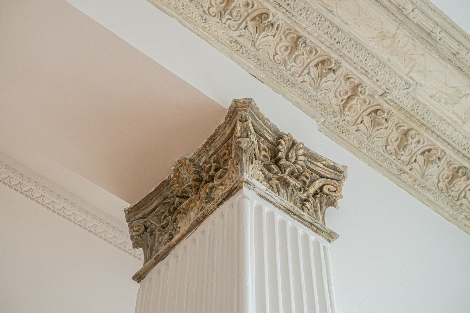 Magnificent stucco work on a column and ceiling of an old building, emphasizing craftsmanship and historical architecture.